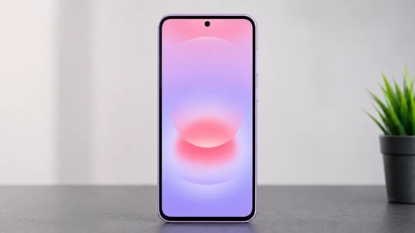 Galaxy A37 5G standing upright on a professional tech table with the screen facing the camera and a small plant in the background.